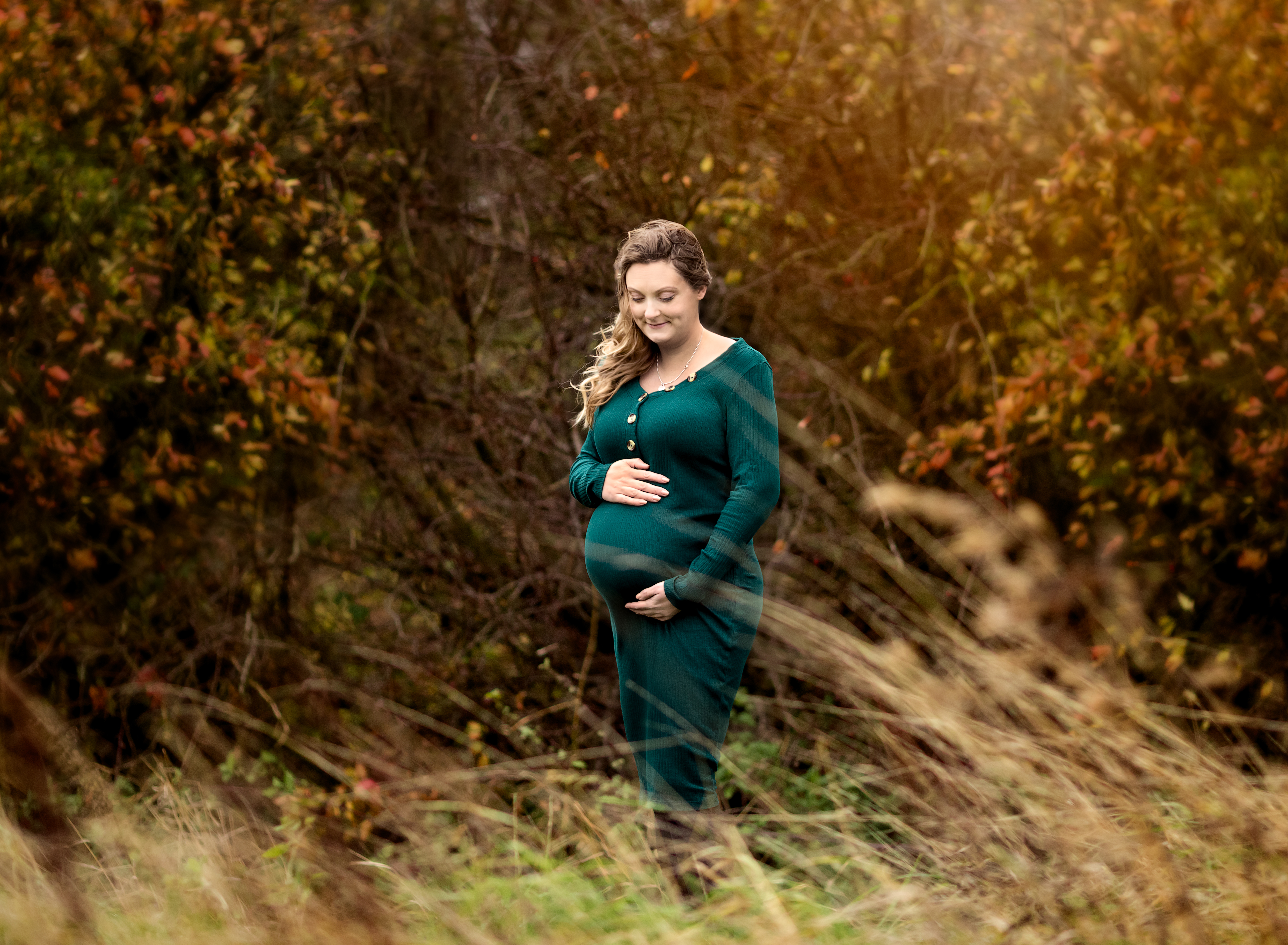 Pregnant woman wearing a green dress in an autumnal outdoor photoshoot with Fairy Nuff photography, Nottingham