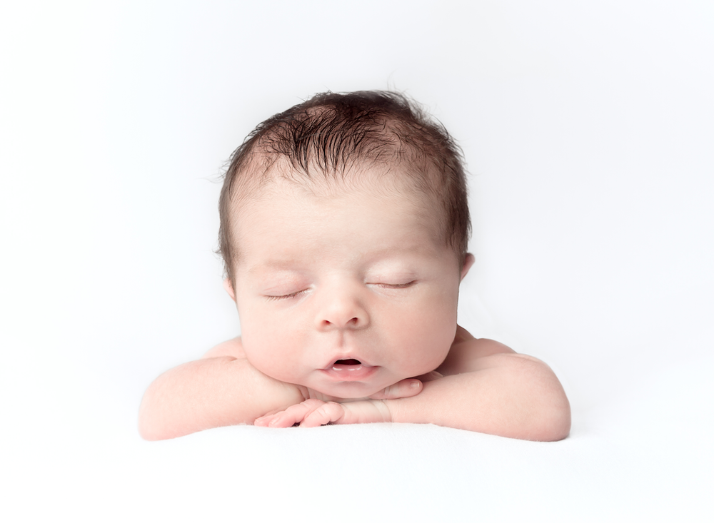 Baby posed in head on hands position on white background