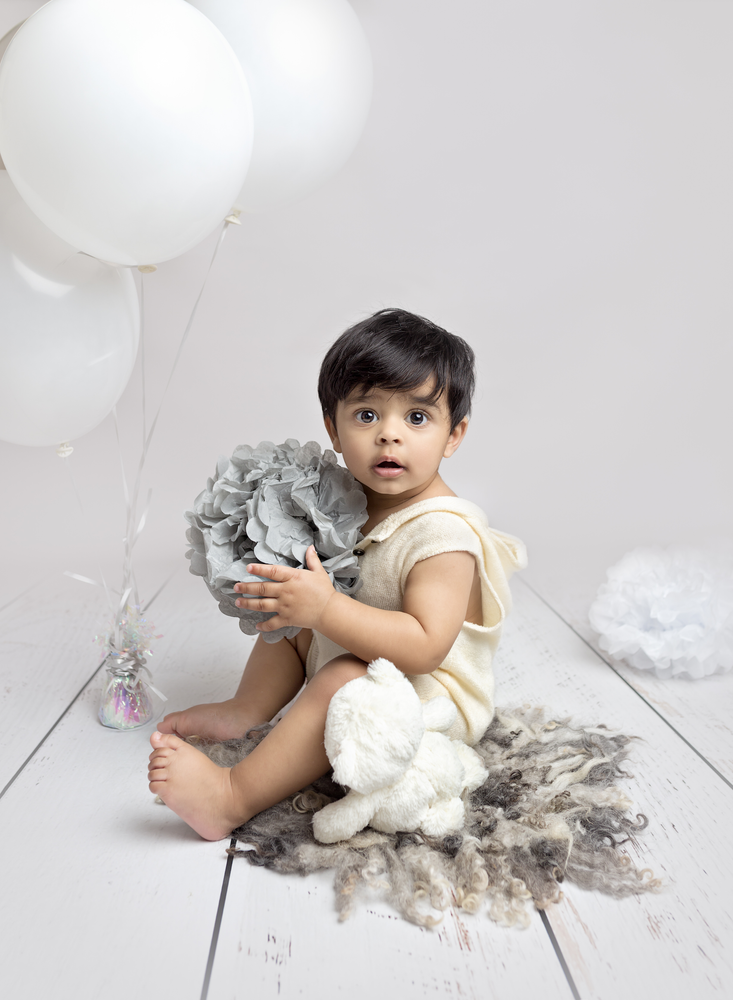 1 year old boy with white balloons on a grey backdrop.  Beautiful 1 year Birthday and cake smash photography, Fairy Nuff photography, Nottingham