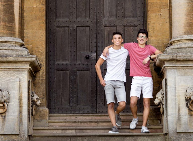 Two teenage Brothers with arms round each other standing outside a country manor in Nottingham UK at a family photo session