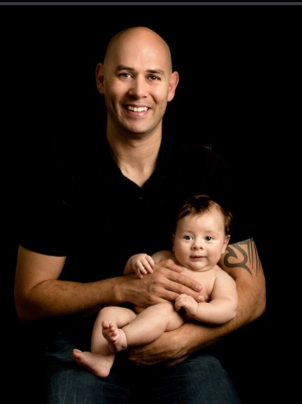 Dad and 16 week old baby Son held in his arms against a black backdrop - Baby Photoshoot at Fairy Nuff Photography Nottingham