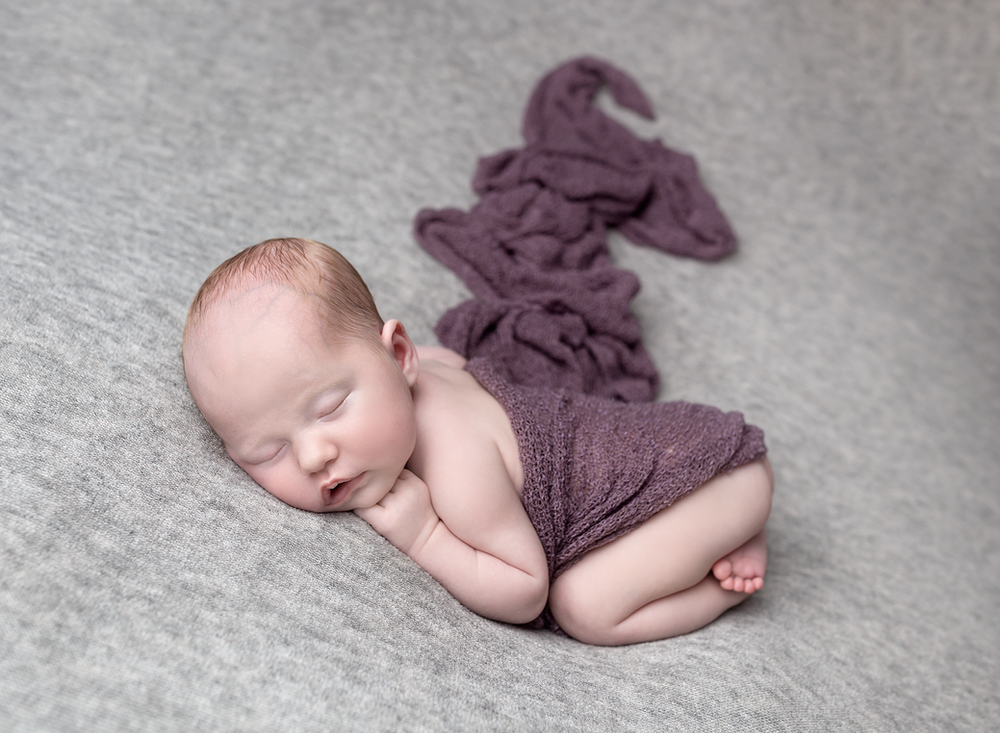 All curled up, a beautiful baby girl in grey and purple. Baby photoshoot - Fairy Nuff Photography, Nottingham