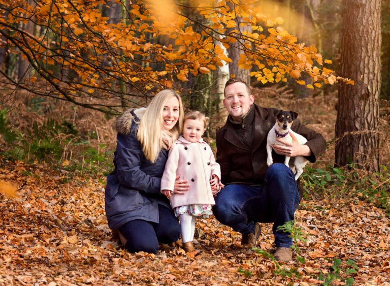 Family group of Mum, Dad, 3 year old girl and dog in a autumn forest during a family photography session in Nottingham UK