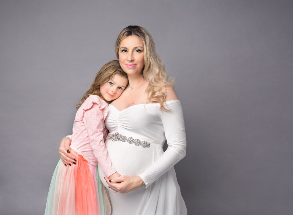 Mum and Daughter posed together cradling baby bump at a bump photoshoot at Fairy Nuff Photography, Nottingham