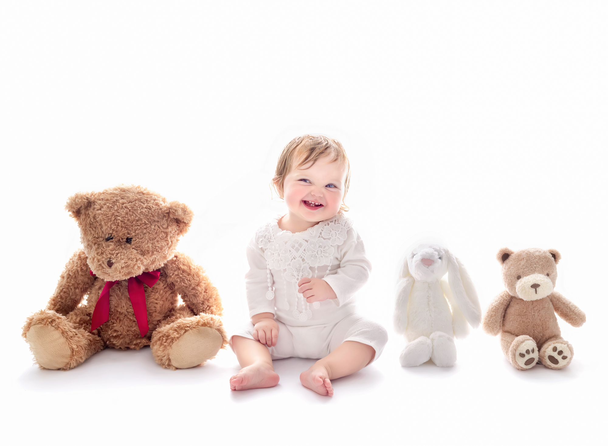 Playing with teddy bears section of 1st Birthday photography session, Fairy Nuff Photography, Nottingham. Baby girl photographed against white with teddies.