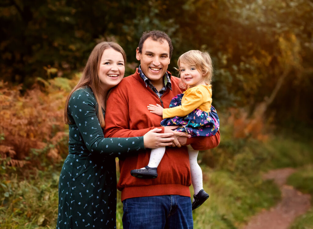 Family of three posed together an Autumn photoshoot in Nottingham by Fairy Nuff Photography