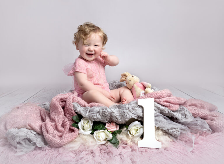 one year old girl in a nest of flowers at her cake smash photoshoot, Fairy Nuff Photography, Nottingham