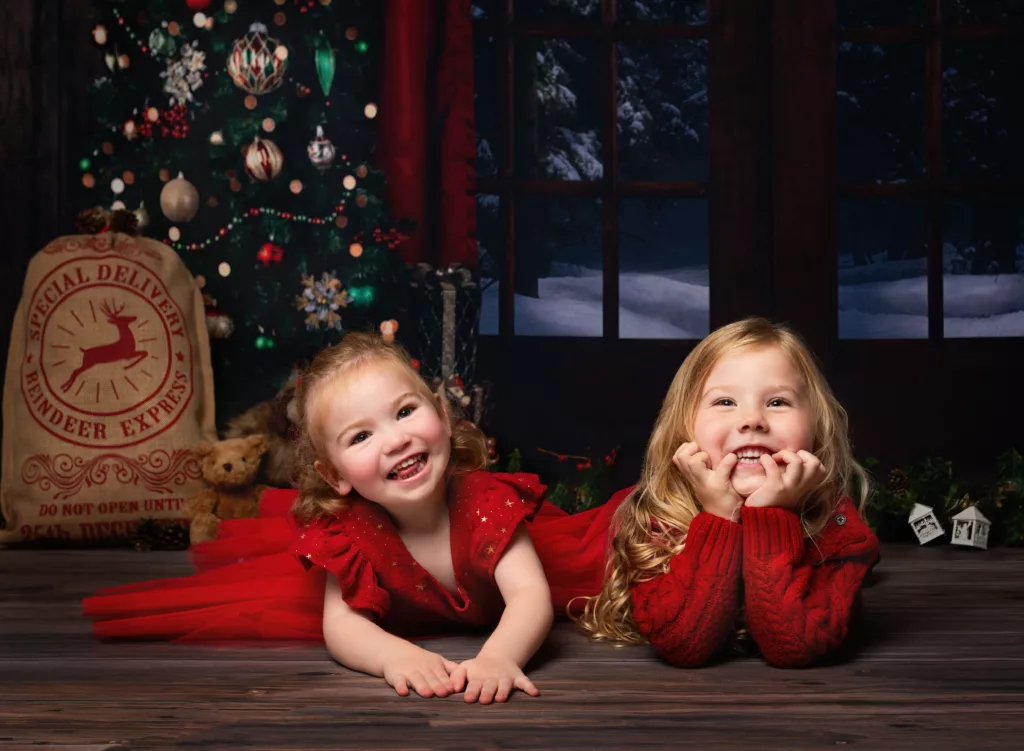 Brother and Sister in Christmas outfits lying on the floor at Fairy Nuff photography's Christmas mini sessions, in Nottingham