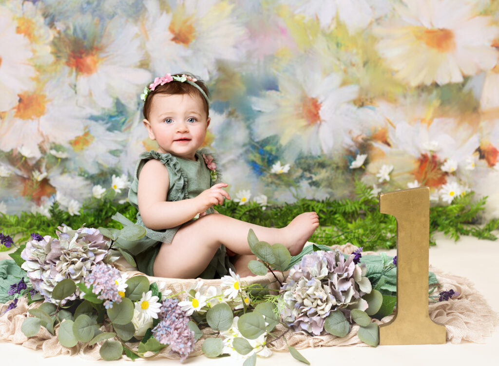 Baby girl in a fresh spring flower set up with daisies and green foliage 1st birthday photoshoot with Fairy Nuff Photography, Nottingham
