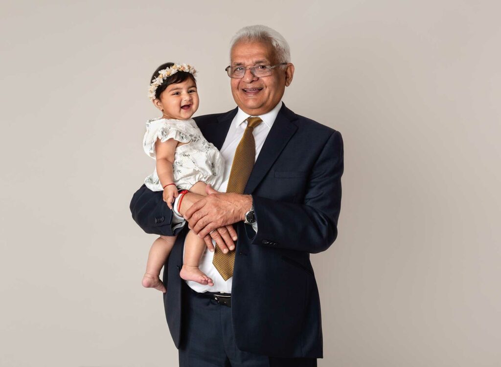 Grandad holding a baby girl in his arms, smiling and happy at family photoshoot at Fairy Nuff Photography, Nottingham